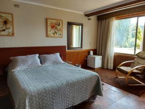a bedroom with a bed and a chair and a window at Complejo Pehuen Lago Lanalhue in Cañete