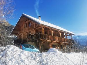 une cabane en rondins avec une voiture garée dans la neige dans l'établissement Chalet Gyronde, à Vallouise
