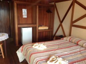 1 dormitorio con 1 cama con toallas en Pousada dos Esquilos, en Campos do Jordão
