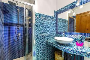 y baño de azulejos azules con lavabo y ducha. en APARTMENT PIED DANS L'EAU, en Golfo Aranci