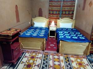 a room with two beds and a desk and a bed sidx sidx sidx at Auberge Des Jardins du Dades in Boumalne