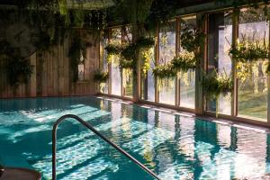 an indoor swimming pool with windows and plants at The Elms Hotel & Spa in Abberley