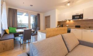 a kitchen and living room with a couch and a table at Ski In Ski Out Apartment Fastenberg Top 2 by AA Holiday Homes in Schladming