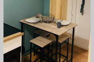 - une petite table en bois avec des assiettes et des ustensiles dans l'établissement Les délices du Havre 15 min du centre ville et de la mer, au Havre