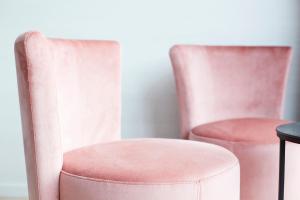 dwa różowe krzesła siedzące obok stołu w obiekcie B&B Armalot by Julia w mieście De Panne