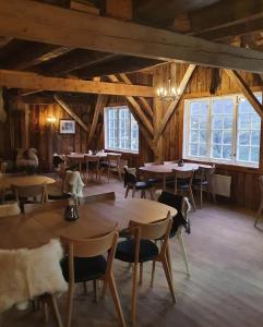 uma sala de jantar com mesas, cadeiras e janelas em Westerås Gard em Geiranger