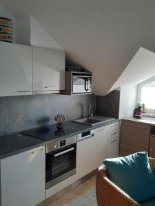 a kitchen with white cabinets and a stove top oven at Kamilla Apartman Villapark in Bük