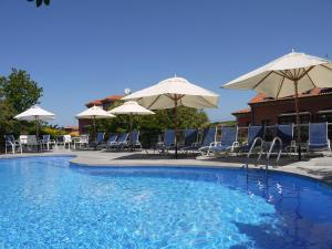 a swimming pool with chairs and umbrellas at Apartamentos Cueto Mazuga I in Po