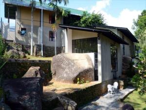 a house with a large rock in front of it at Dream Lodge in Kandy