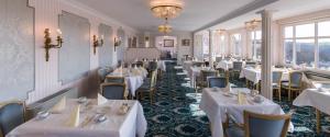 un ristorante con tavoli e sedie bianchi e finestre di Gästehaus Plönlein - Hotel Goldener Hirsch Rothenburg a Rothenburg ob der Tauber