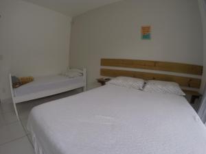 um quarto com uma cama branca e um banco em Florianópolis Pousada Moçambeach em Florianópolis