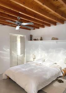 1 dormitorio con 1 cama blanca y ventilador de techo en Cortijo el Grillo, en Níjar