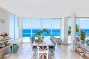 a dining room with a table and views of the ocean at Bay Reflections Camps Bay Luxury Serviced Apartments in Cape Town