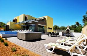 a group of chairs sitting on a deck next to a house at Villa Bahamas by Algarve Vacation in Armação de Pêra