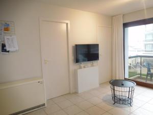 a living room with a television and a table at Bella Plaza in De Panne