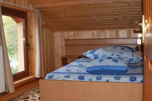ein Schlafzimmer mit einem Bett in einer Hütte mit einem Fenster in der Unterkunft Cabana Suprema Armonie in Dâmbovicioara