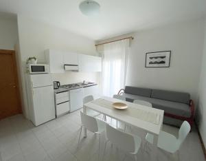 eine Küche und ein Wohnzimmer mit einem Tisch und einem Sofa in der Unterkunft Dainese Apartments, Casa Ester in Lido di Jesolo