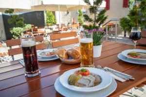a wooden table with plates of food and two glasses of beer at Klostergasthof Heidenheim in Heidenheim