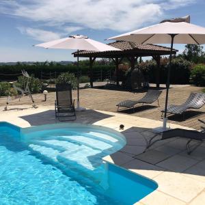 - une piscine avec des chaises et un parasol dans l'établissement DOMAINE D'ELUSA, à Vic-Fezensac