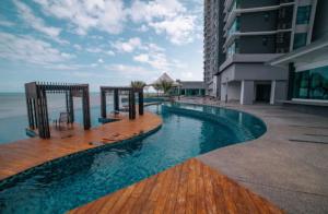 a swimming pool next to a building next to the ocean at Cozy Seaview Studio at Imperium residence Tanjung Lumpur Kuantan in Kuantan