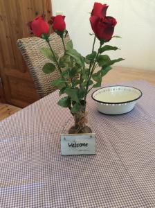 un vase avec des roses sur une table dans l'établissement Altes Pastorat Langenhorn, à Langenhorn