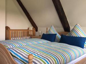 a bed with a striped comforter and two pillows at Altes Pastorat Langenhorn in Langenhorn
