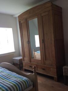 einen Holzschrank mit einem Spiegel im Schlafzimmer in der Unterkunft Altes Pastorat Langenhorn in Langenhorn