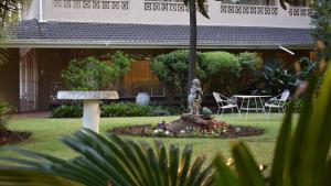 einen Garten mit einer Statue vor einem Haus in der Unterkunft Moye Guest House in Benoni