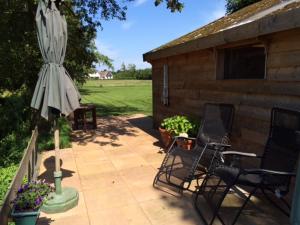 胡弗拉肯的住宿－The Old Barn，一座带两把椅子和一把遮阳伞的庭院以及一座建筑