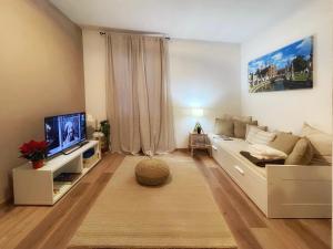 ein Wohnzimmer mit einem Sofa und einem TV in der Unterkunft CIVICO 57 Al Santo - PADOVA in Padua