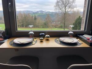 a table with plates and a window with a view at By Chris in Malmedy