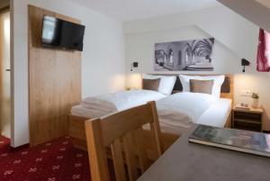 a bedroom with a bed and a table and a television at Klostergasthof Heidenheim in Heidenheim