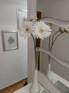 two white vases with white flowers in them at Deluxe Apartment MyPlace in Osijek