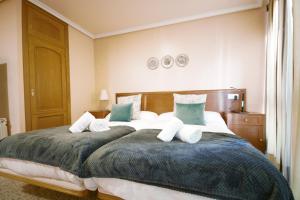 a bedroom with two beds with blue and white pillows at H. O Lar in O Barco de Valdeorras