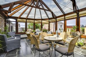 a conservatory with chairs and tables and a glass roof at Hotel La Crémaillère in Jalhay