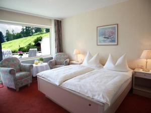 a hotel room with a bed and two chairs and a window at Gästehaus Kramer - Emde in Willingen