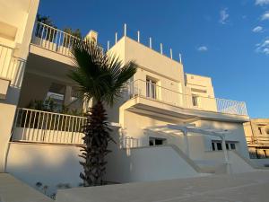 un edificio bianco con una palma di fronte di Residence Valentina - Apartment Leonardo int 8 a Santa Maria al Bagno