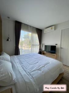 Un dormitorio con una gran cama blanca y una ventana en Play Condo Chiang mai MAYA en Chiang Mai