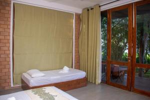 a bedroom with a bed and a window with a patio at Breezy Lake in Tissamaharama