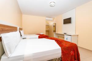 a hotel room with two beds and a tv at Jardim dos Orixás in Canoa Quebrada