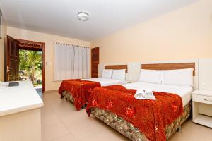 two beds in a hotel room with red sheets at Jardim dos Orixás in Canoa Quebrada