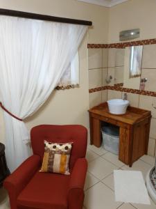 baño con silla roja y lavamanos en Blue Rain Guest House, en Upington