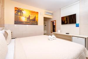 a bedroom with a white bed and a tv at Jardim dos Orixás in Canoa Quebrada +161 photos