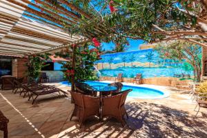 eine Terrasse mit einem Tisch und Stühlen sowie einem Pool in der Unterkunft Jardim dos Orixás in Canoa Quebrada