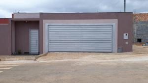 een gebouw met twee garagedeuren op een parkeerplaats bij Casa para temporada primavera na canastra in São Roque de Minas