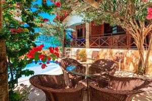 un patio con una mesa de cristal, sillas y flores en Jardim dos Orixás en Canoa Quebrada