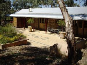 a house with a patio with a table and a tree at 1860 Wine Country Cottages in Springton