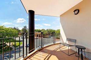 a balcony with a chair and a view of a street at AAC Apartments - Griffin in Canberra