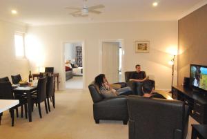 a group of people sitting in a living room watching tv at Brayfield Cottage in Murray Bridge