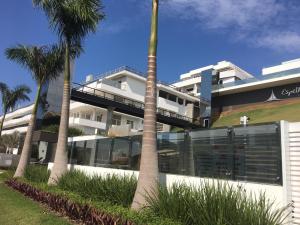 a building with palm trees in front of it at Apartamento Moderno - Piscina Borda Infinita - Vista magnífica para o mar in Florianópolis